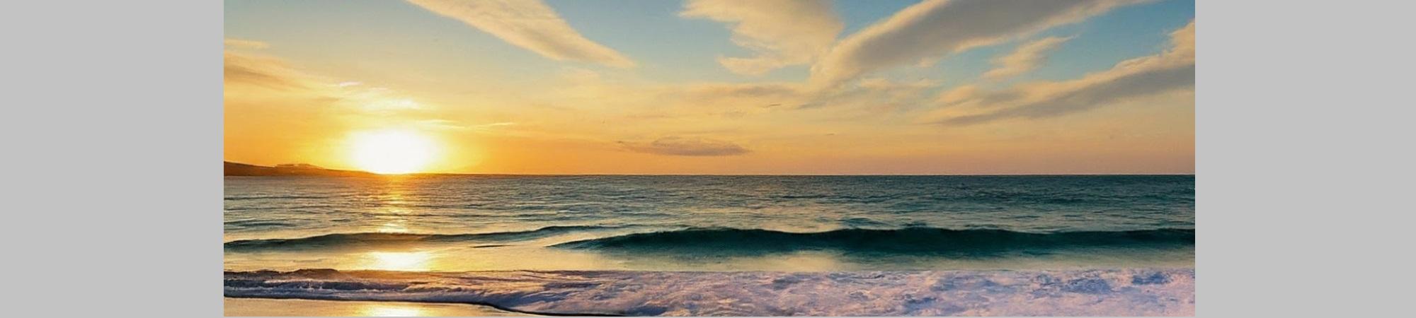 Calm surf waves, sunset, blue sky, orange distance. 